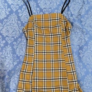 Yellow plaid mini dress with black straps.